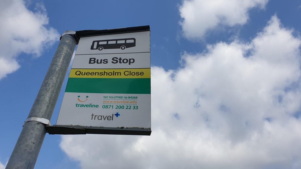 Bus stop sign against background of sky.