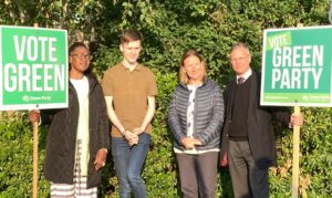 Four people in a line with large Vote Green posters.